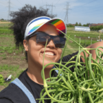 Young woman with rainbow visor holding freshly harvested green beans